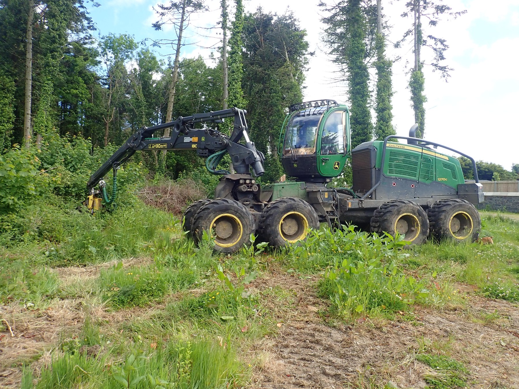Cały harwester John Deere 1270G w lesie, z kabiną, kołami i wysięgnikiem